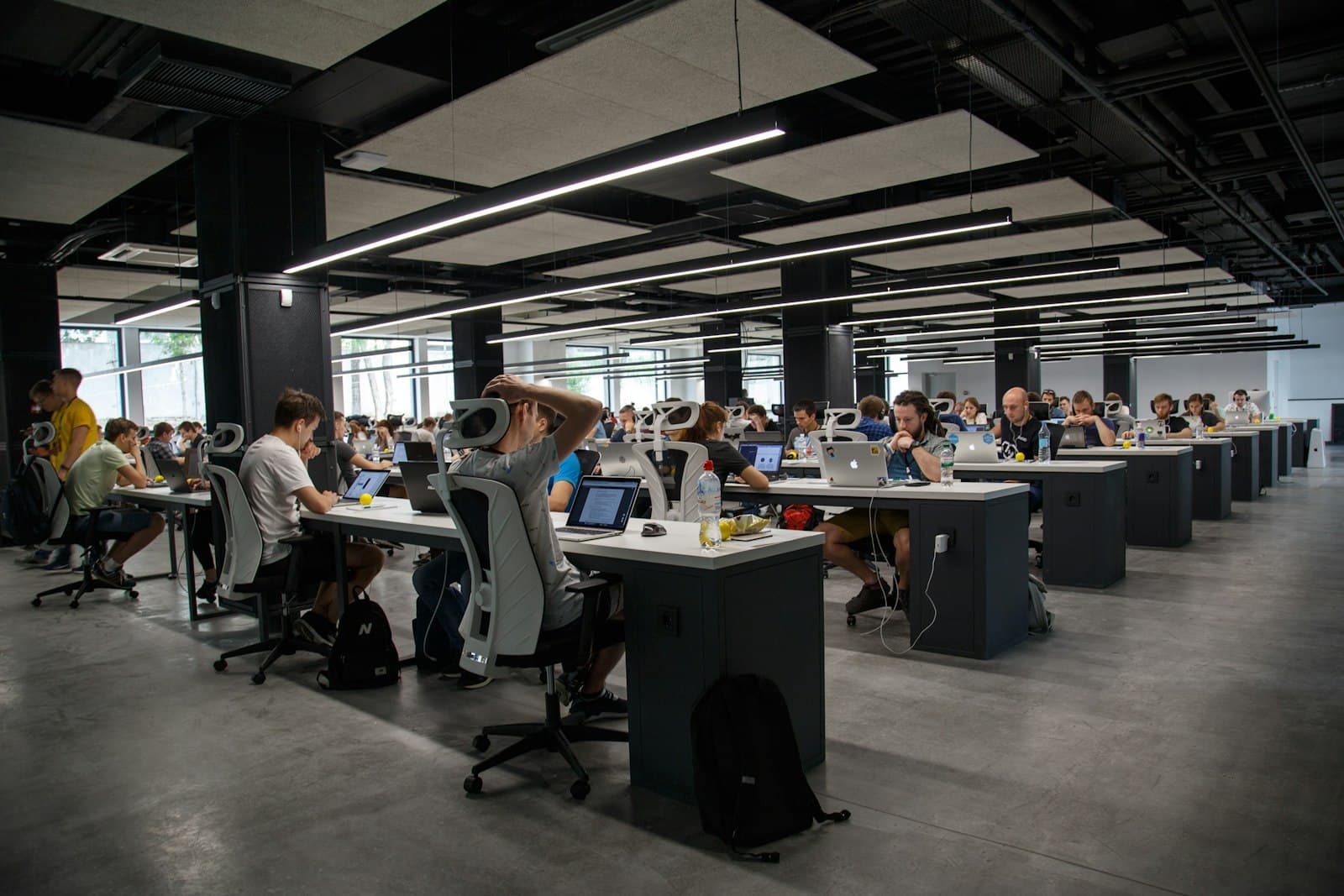Large open-plan office with rows of people working on laptops